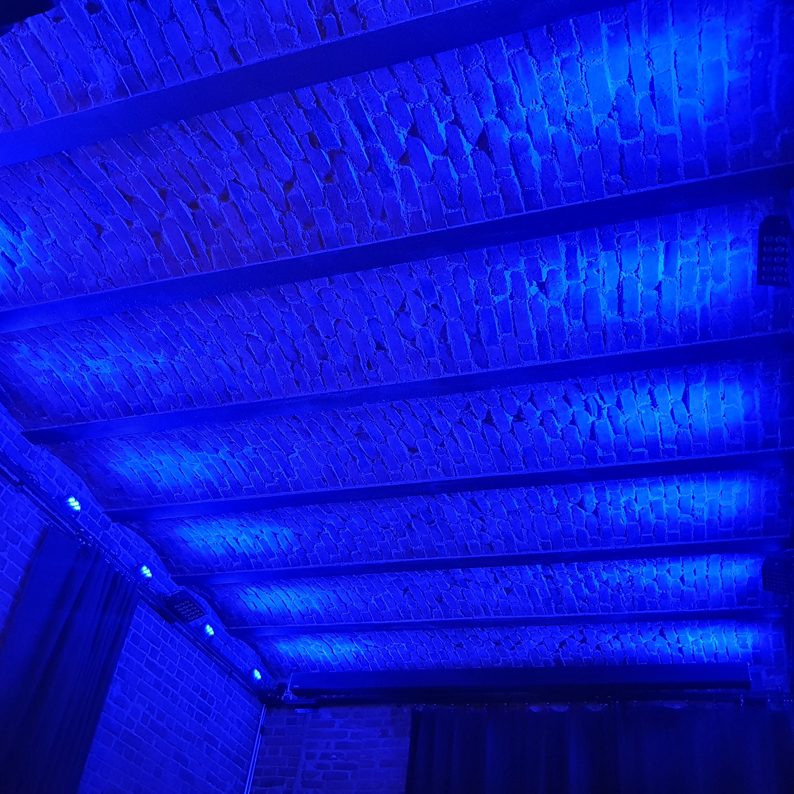 Red brick ceiling with steel railway track girders in Kammio bathed in blue light