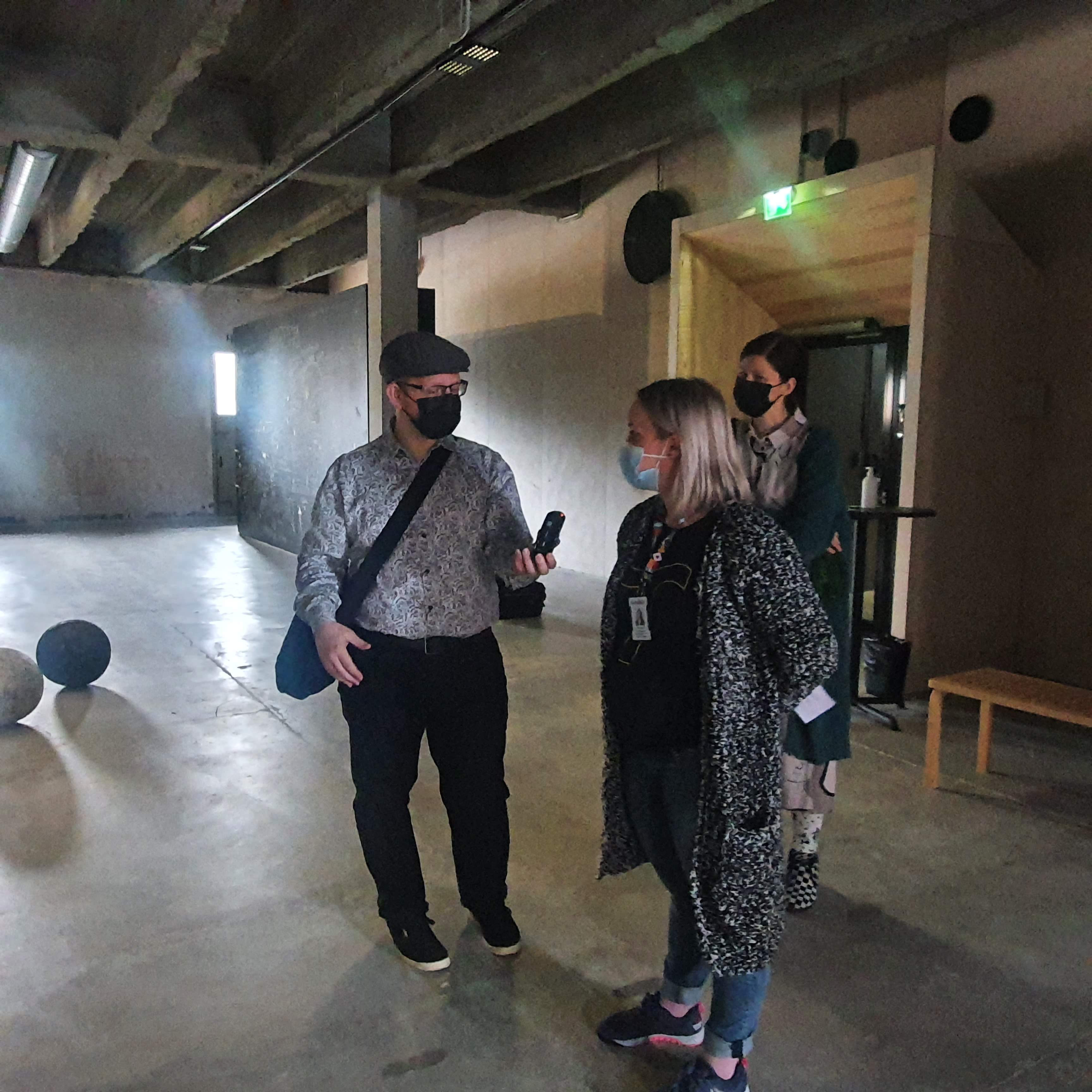 Mark interviewing Elina and Pävi in a bare, concrete room. Calix exhibition by Päivi Rintaniemi