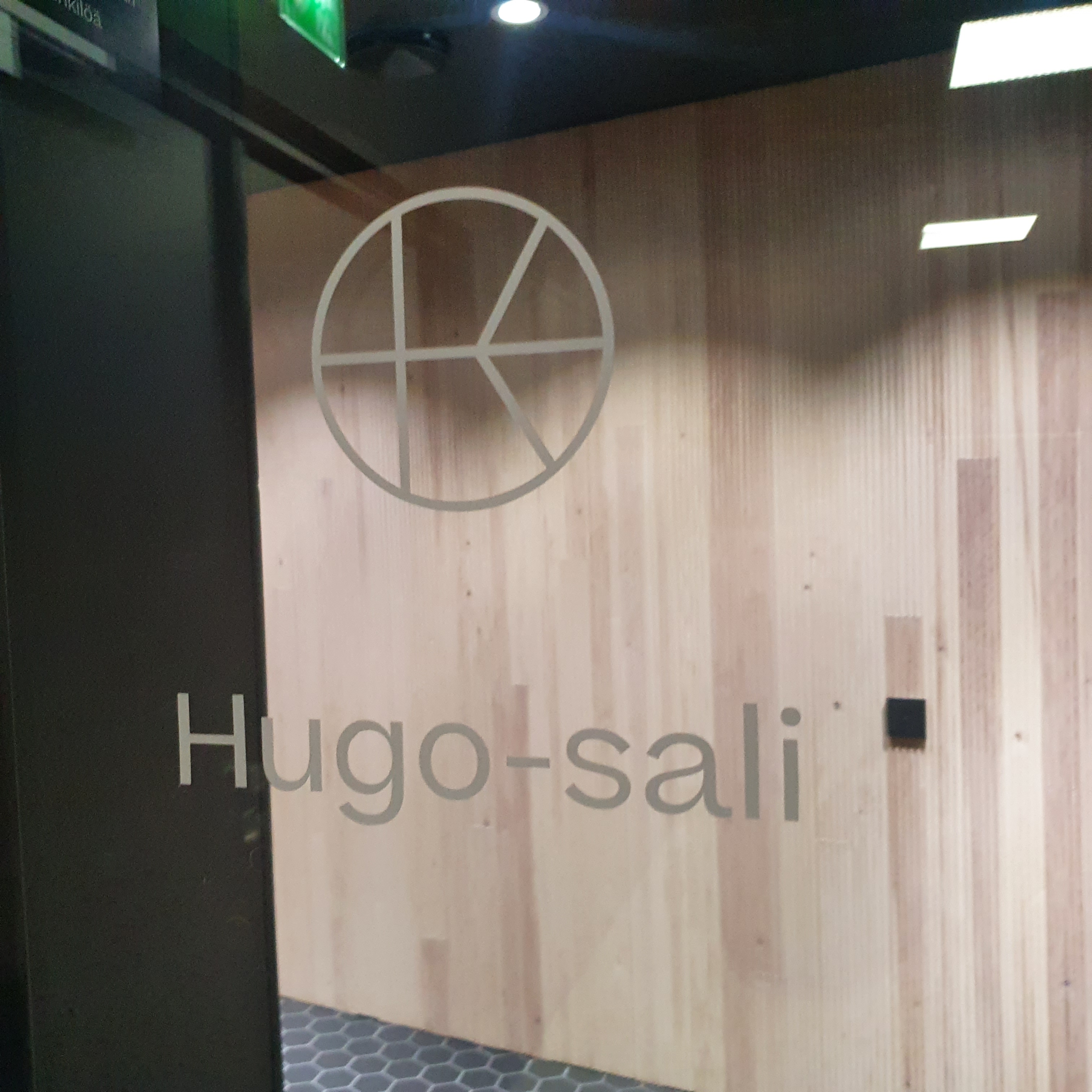 Glass door with a white logo reading Hugo sali