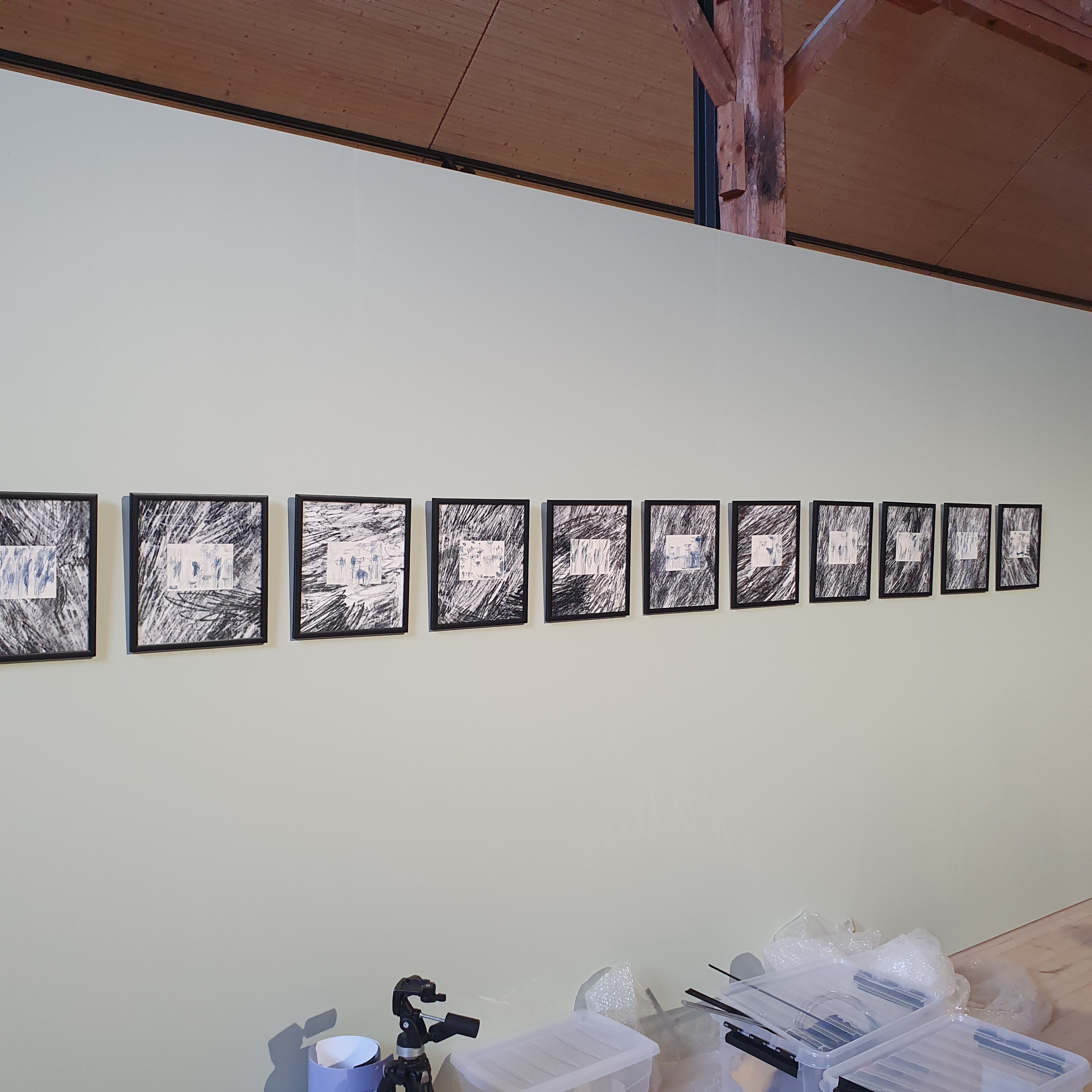 A row of pictures from the “Stump of Prometheus – Stay together” exhibition hung on the wall in black frames