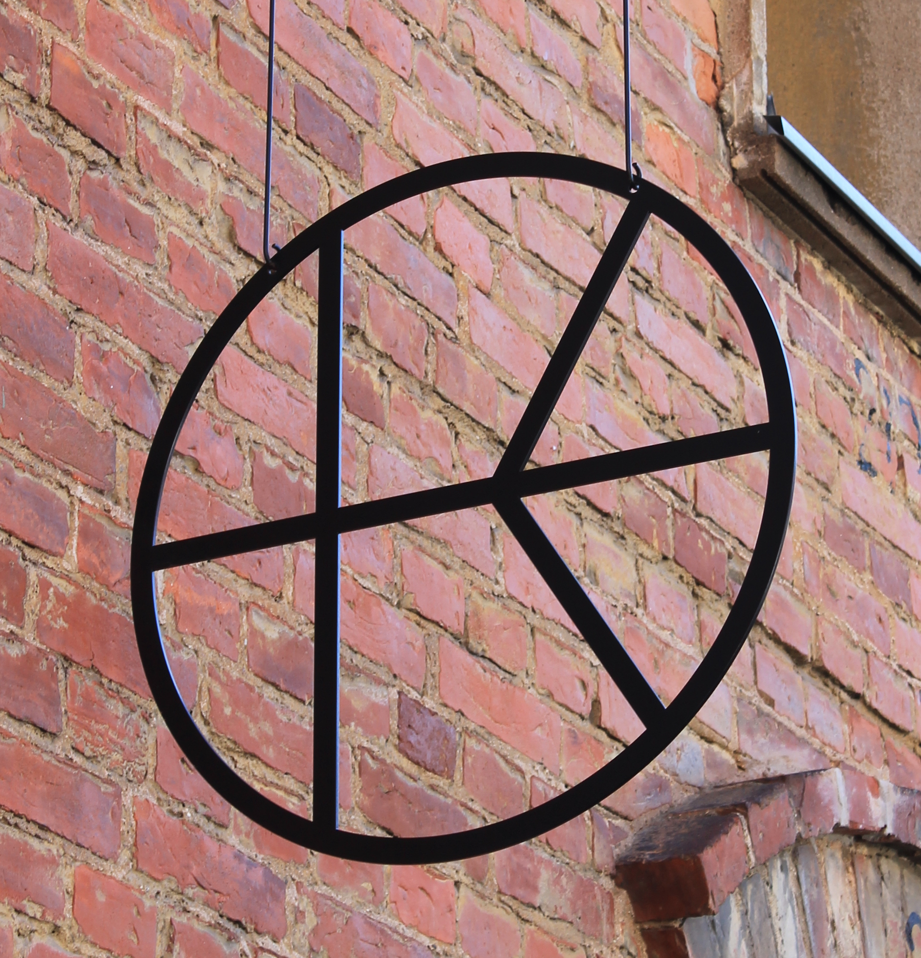 Black metal hanging sign of Kalevan Navetta logo, inspired by the round window in Vintti