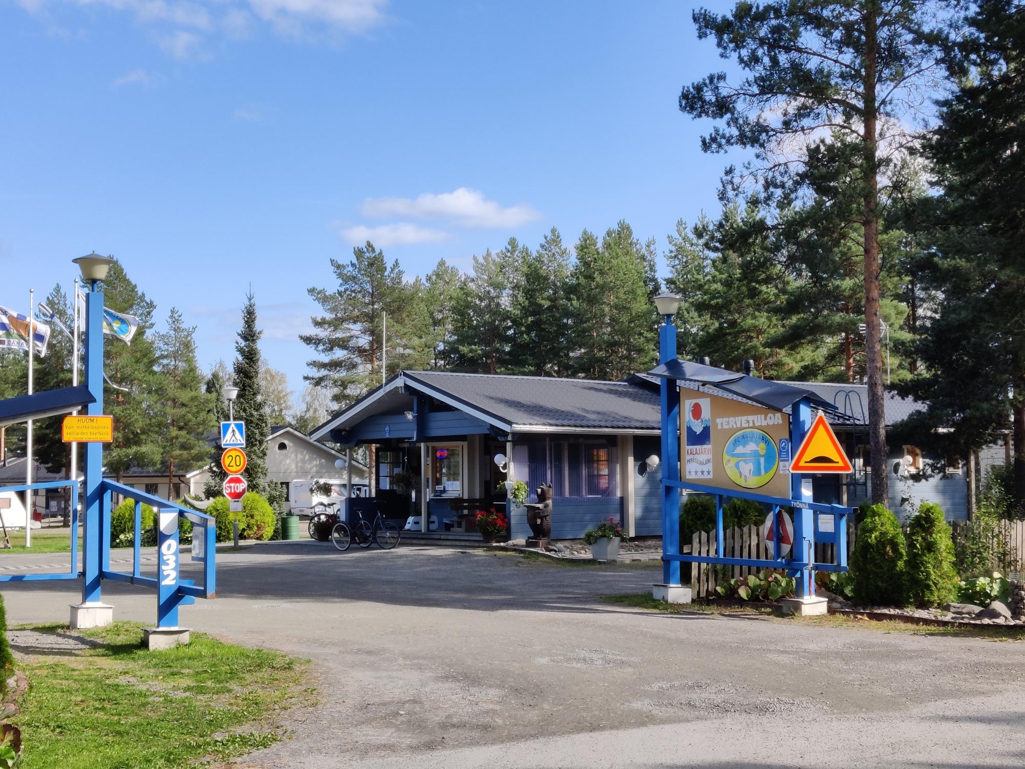 The entrance gates at SF-Caravan-Kalajärvi in summertime, the trees are green and the sky is blue
