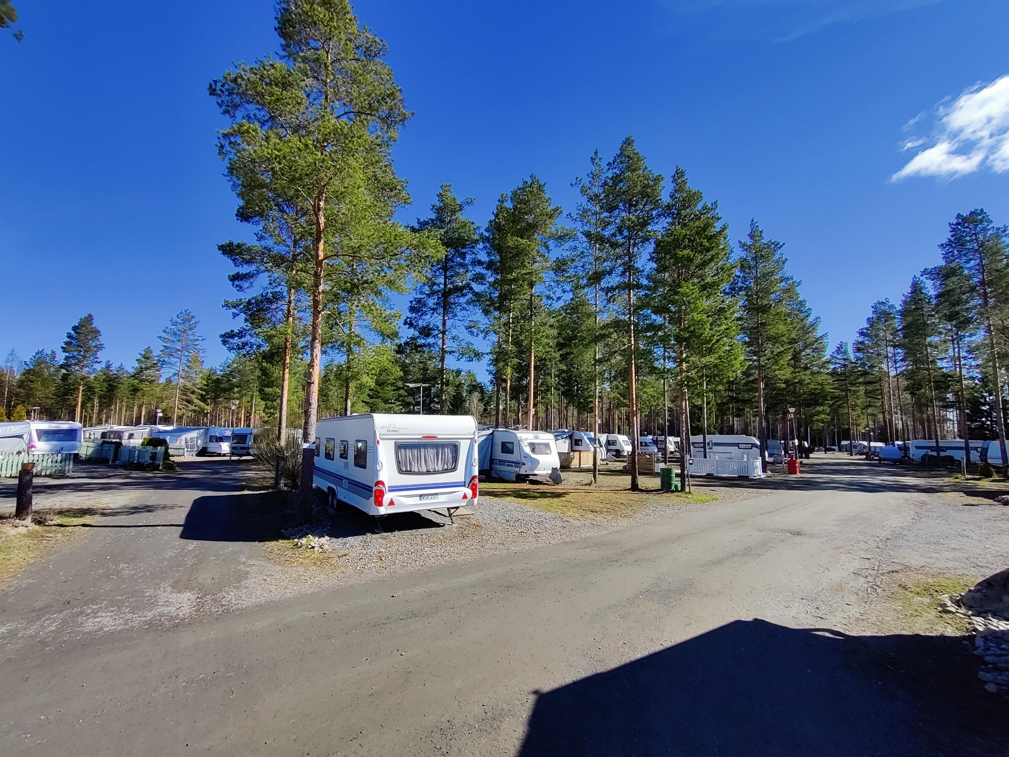 Caravans at SF-Caravan-Kalajärvi with tall trees and a blue sky