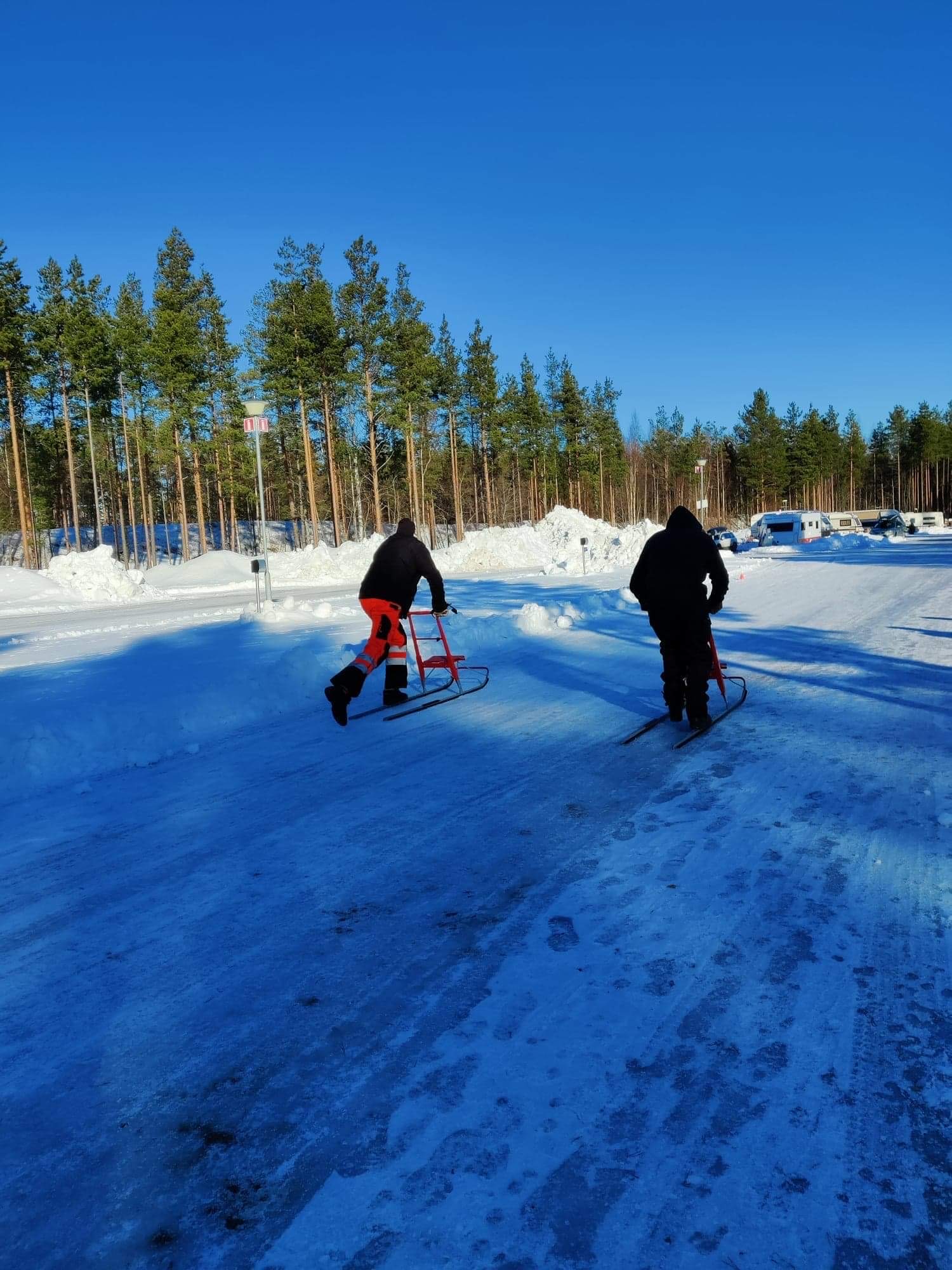 Two people travelling along an icy track on kick sleds