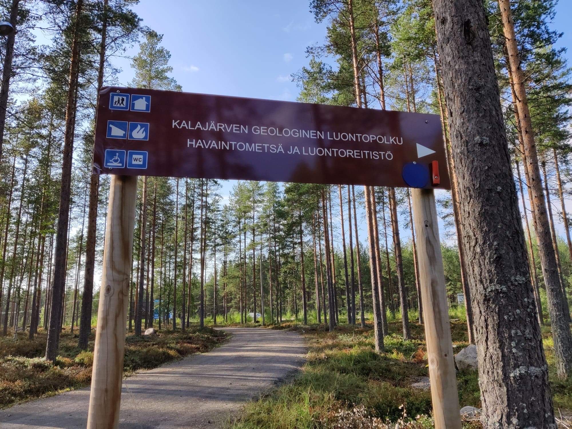 Brown sign showing the way to the nature trail (or luontopolku) in the woods near SFC-Kalajärvi