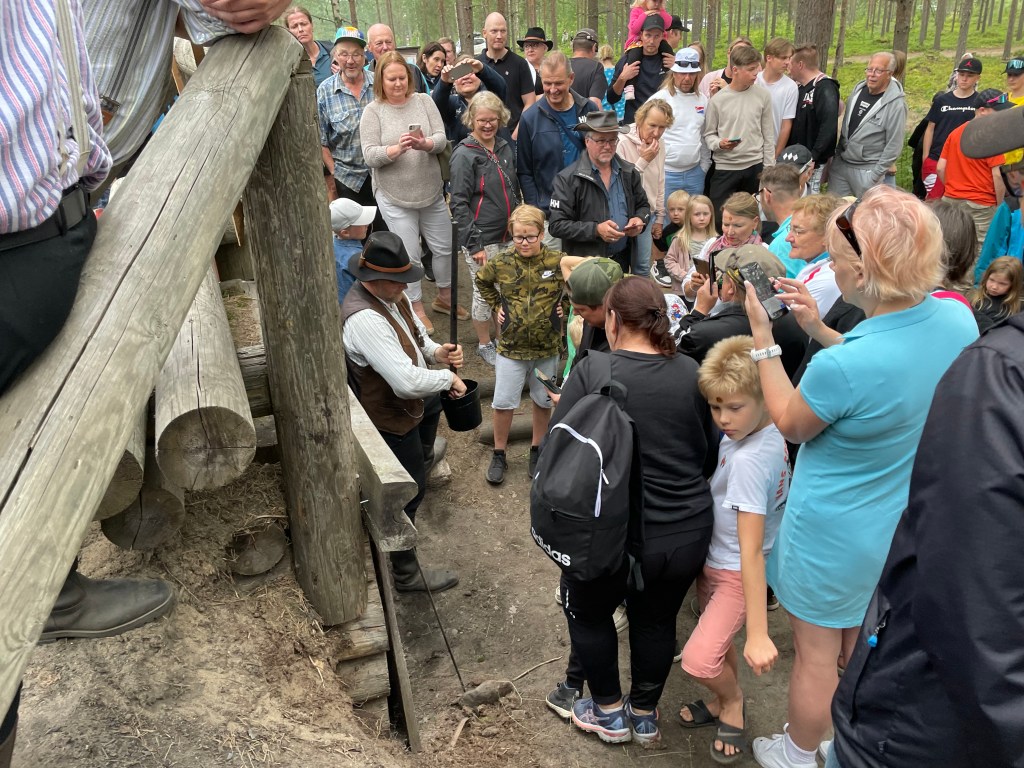 A crowd of people around a man in traditional costume, waiting for a 'tar blessing'.